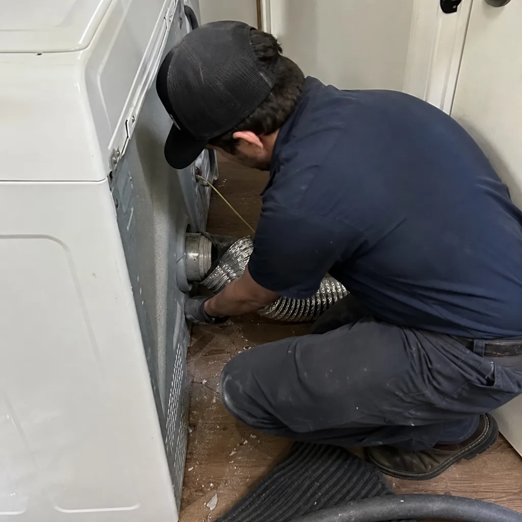 Technician performing professional dryer vent cleaning and maintenance service
